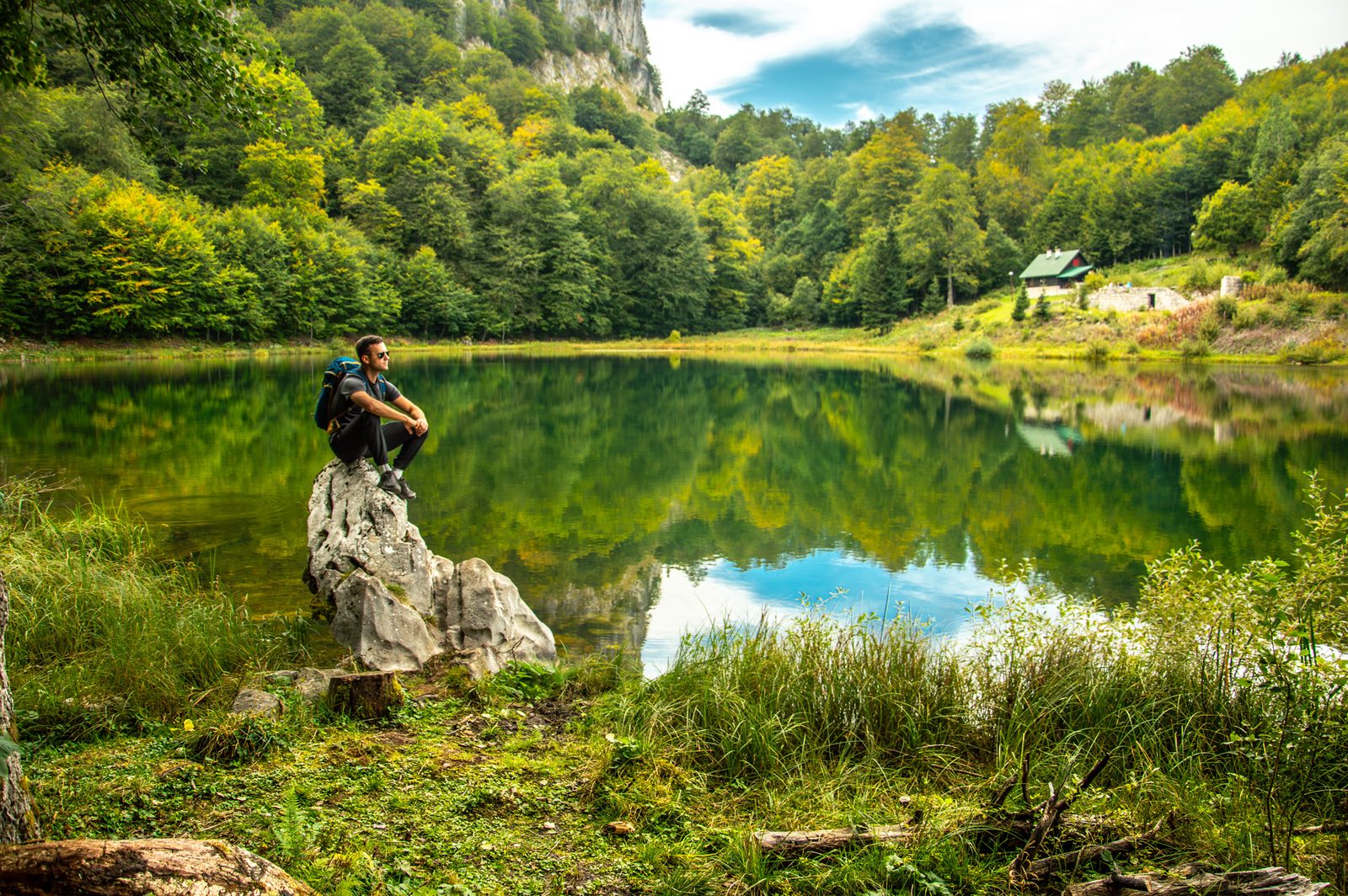 A hiker enjoys the view of a calm mountain lake surrounded by forest