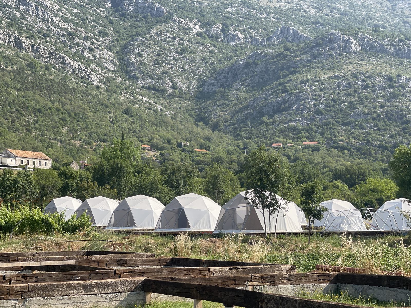 White glamping domes at the foot of a rocky mountain