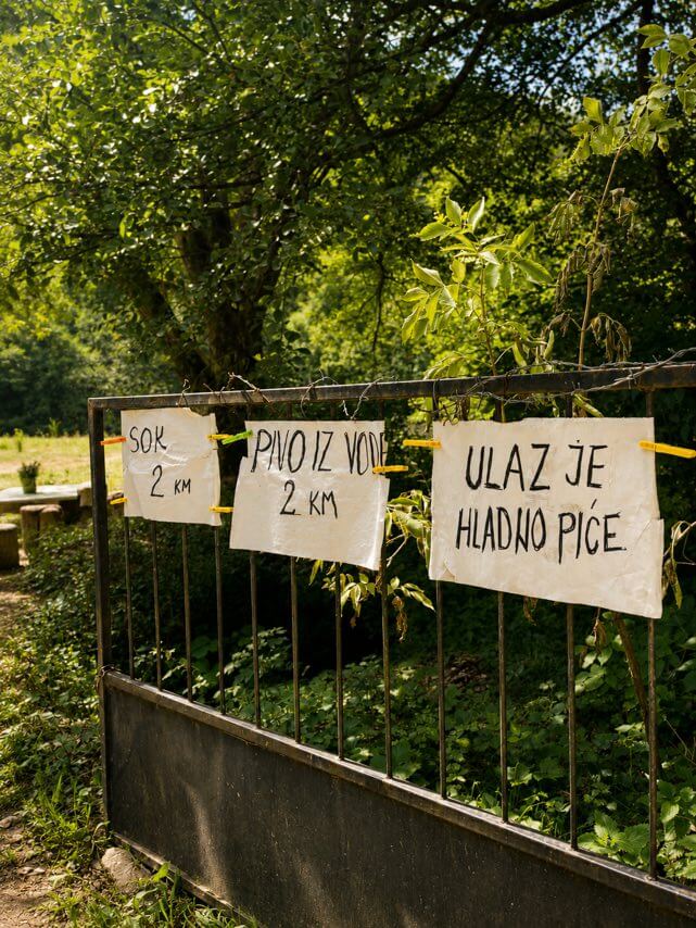 A gate with handwritten signs: juice 2 KM, beer from the water, entrance is a cold drink