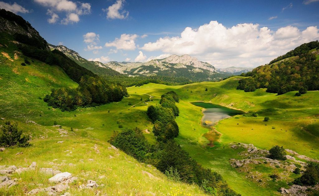 Planinski pejzaž Nacionalnog parka Sutjeska s jezerom usred zelenih livada